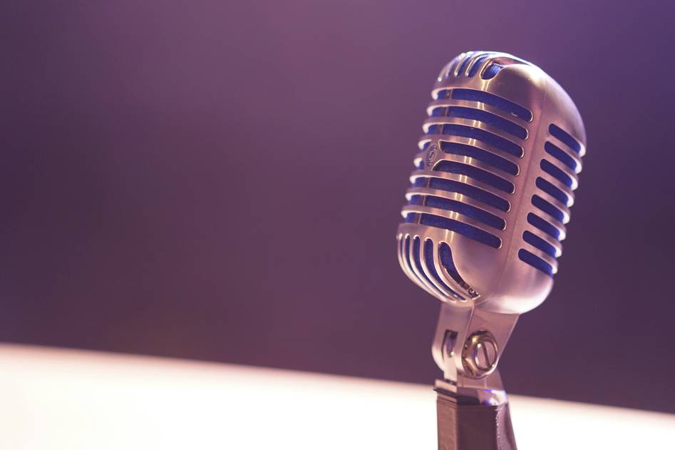 Podcast microphone with headphones on wooden table